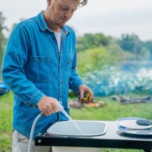 Man washing up on side table of Tear Drop camper